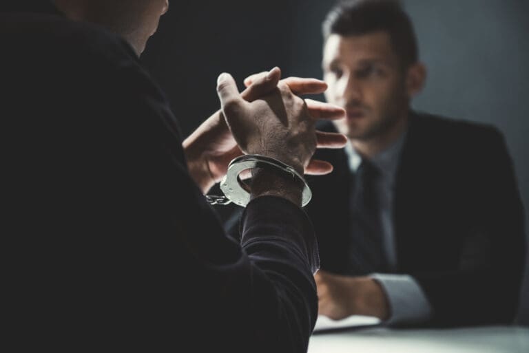 Handcuffed man being interviewed in interrogation room