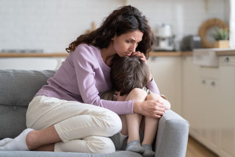 Mother comforting crying child on sofa